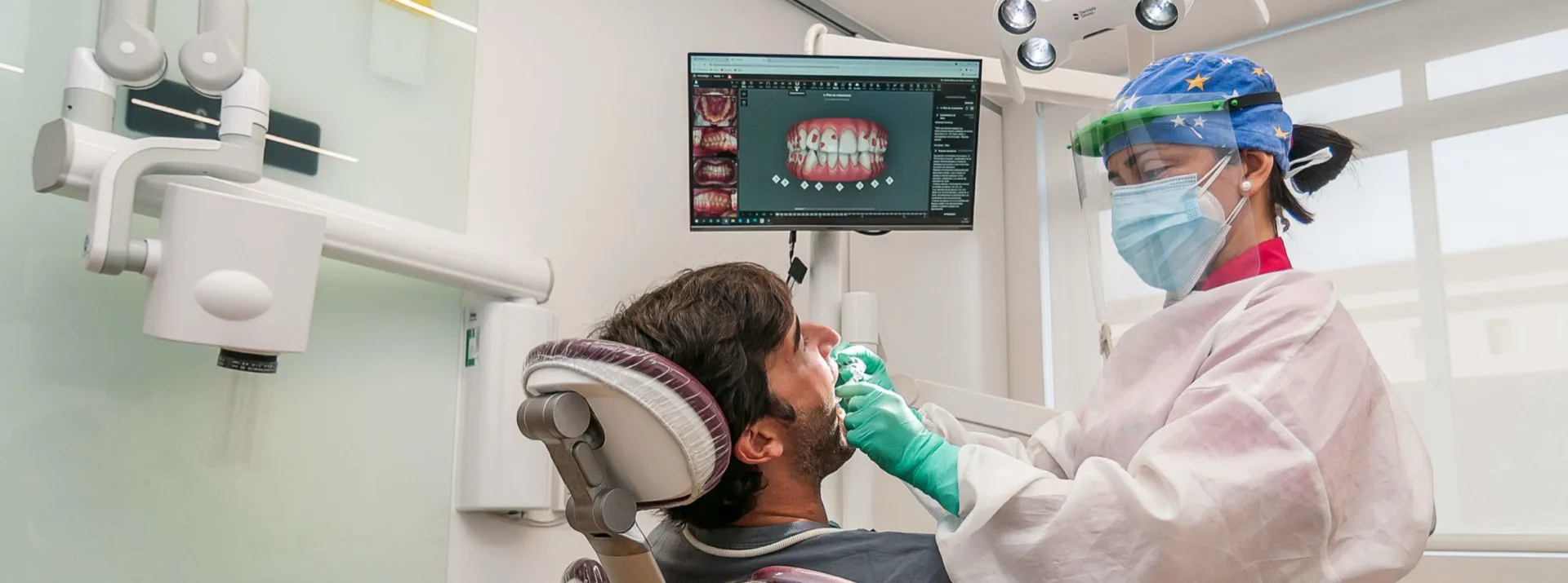 Profesional de Clínica Dental San Salvador tratando a un paciente en el gabinete, con la planificación digital en pantalla