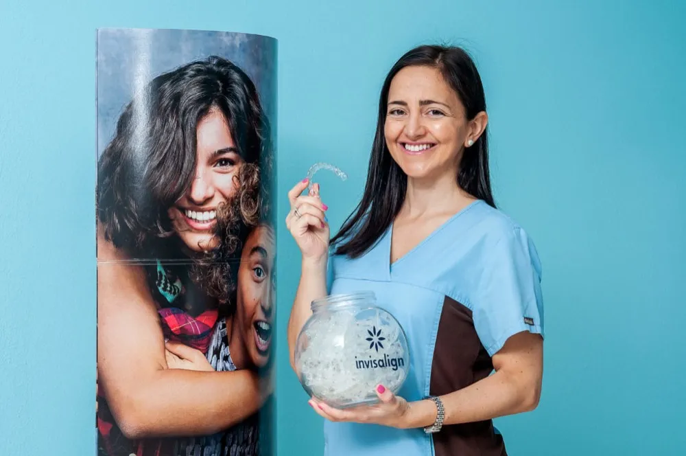 Profesional de Clínica Dental San Salvador sosteniendo un bote de alineadores Invisalign